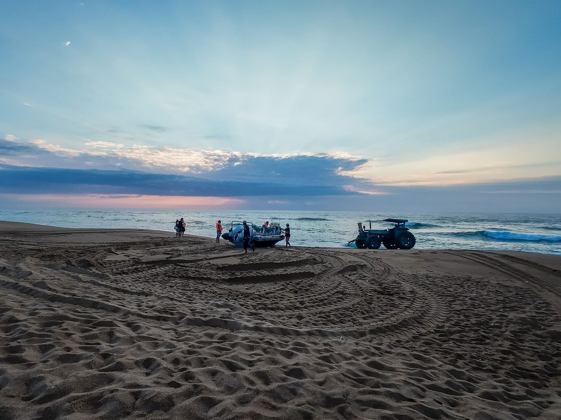 Crew, tractor and boat lined up on the beach at first light before a surf launch