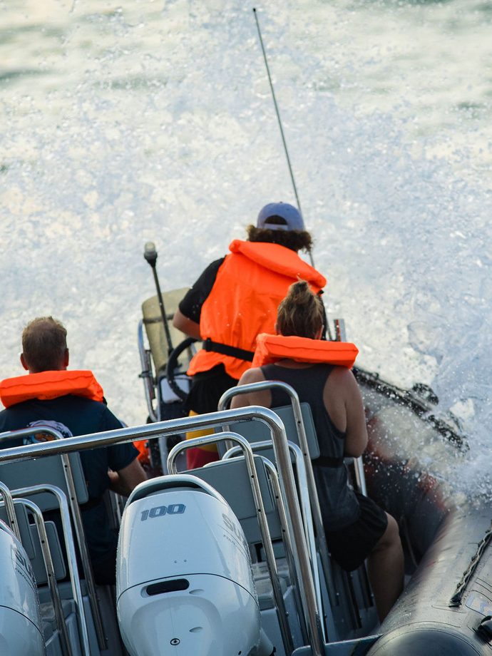 Twin Suzuki outboards on the transom of a rigid inflatable boat with the crew seated ahead of them