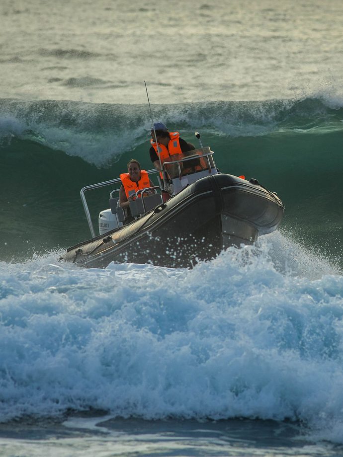 A skipper taking a rigid inflatable boat over a breaking wave