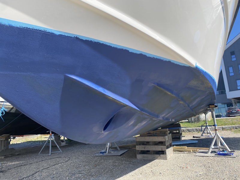 Freshly antifouled blue hull of a boat standing on cradles