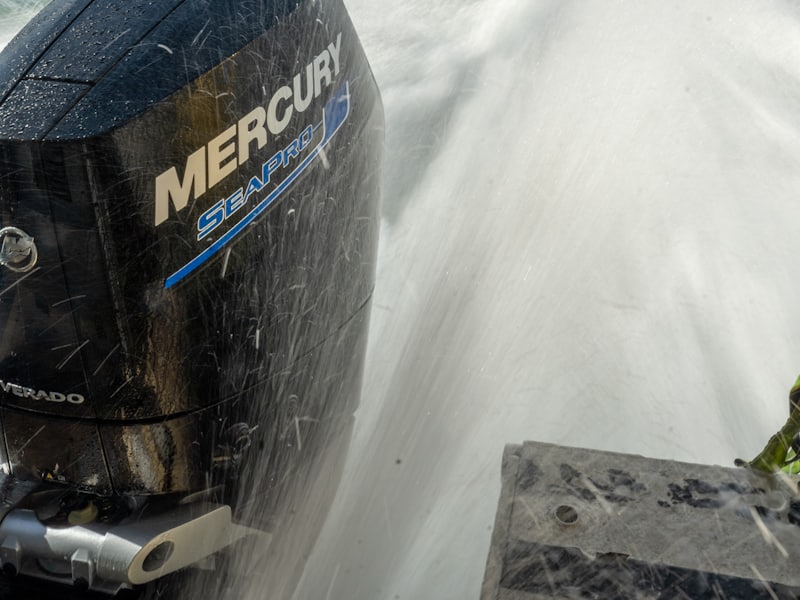 Spray flying off an outboard motor as a boat powers through the water