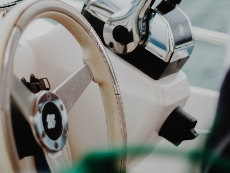 Close-up of a chrome throttle control and wheel at a boat's helm