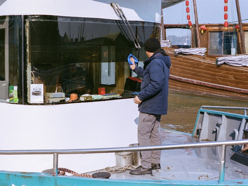 A worker cleaning the windows of a boat's cabin