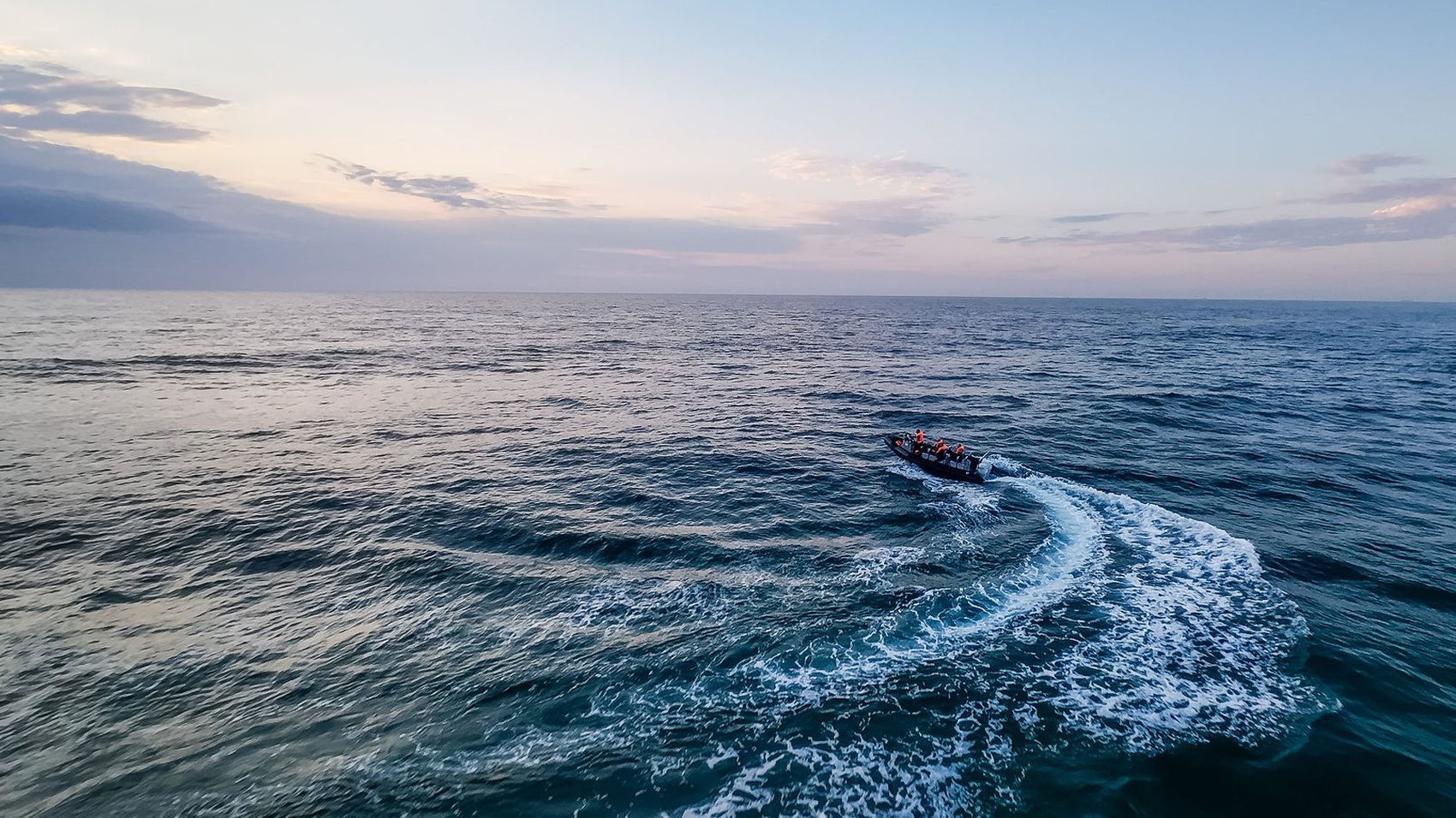 Aerial view of a rigid inflatable boat carving a wake across open water at sunrise off the KZN North Coast